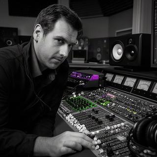 Fateh Dewinter aan een audiomengtafel met meters en studioapparatuur